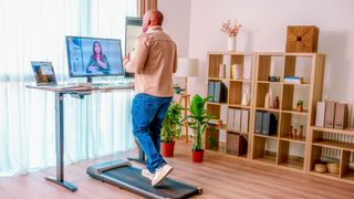 A man working in front of a laptop while taking steps on one of the best walking treadmills