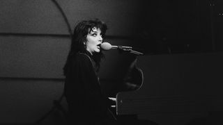 A black and white photo of Kate Bush singing in concert