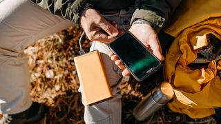 Person outside using one of the best power banks to charge smartphone 