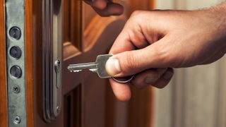 A hand reaching a key into a lock