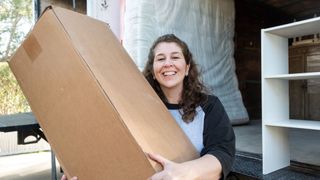 A woman holds a mattress in a box that has been purchased from Amazon