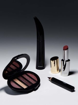 Byredo beauty makeup collection with mascara in black case, eyeshadow palette with five shades of red, red eyeliner pencil, and red lipstick