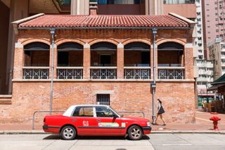 Red brick building in West Kowloon, with taxi in front