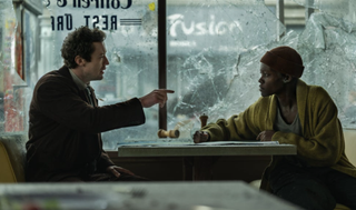 a man and woman sitting in a restaurant with broken windows