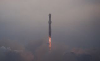 a massive silver rocket lifts off above a plume of fire