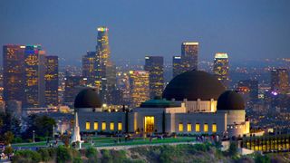 a white building with a large dome in the center lit up at night with city lights behind it