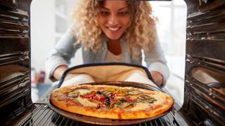 A pizza being put in the oven on a tray