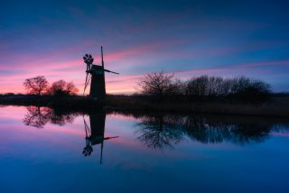 A sunset photo of a silhouetted windmill