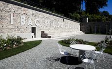 Public space with pebbles. greenery and white table and chairs