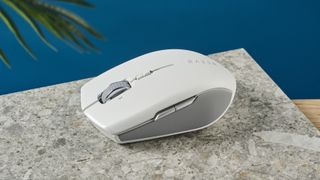 A white Razer Pro Click Mini wireless mouse on a marble slab