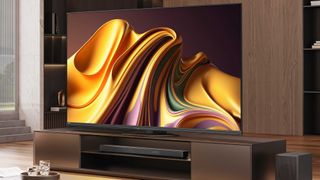 The Hisense U8N TV on a wooden media unit in front of a wooden shelving unit. On screen is a wavy graphic in mostly gold, with purple and green elements.