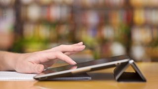 A person's hand using a tablet, up close and from the side