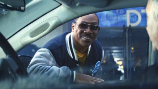 Eddie Murphy wears sunglasses and smiles while talking through a car window in Beverly Hills Cop: Axel F.