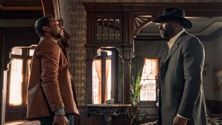 Jonathan Majors and Idris Elba stand face-to-face as Nat Love and Rufus Buck in The Harder They Fall