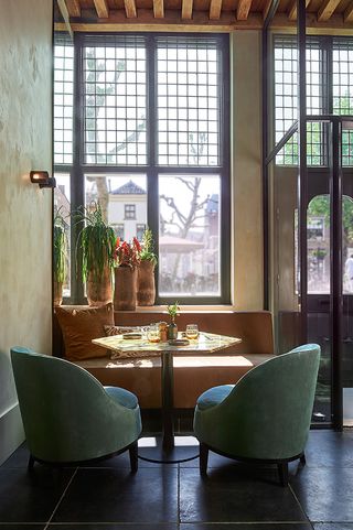 Couch with 2 single cushioned chairs around table infront of window and next to an entrance