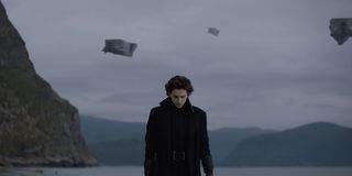 Paul Atreides (Timothee Chalamet) wears a long black coat as he walks on a beach in 2020's Dune