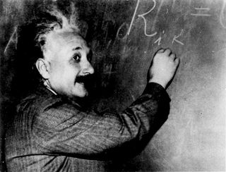 Albert Einstein writing on a blackboard.