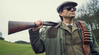 Lord Tony Baddingham (David Tennant) poses with a shotgun over his shoulder in "Rivals"