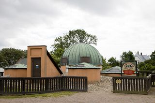 A small dome and several other buildings against a cloudy sky.