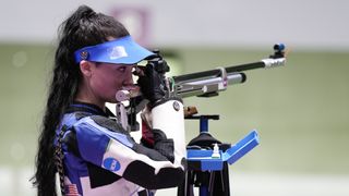 Mary Tucker takes aim at the 10m Air Rifle Women's event at the Olympic Games, wearing a blue and white jacket and blue visor.