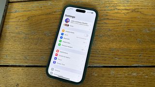 An iPhone on a desk showing the Settings app to help you reset your Apple ID password