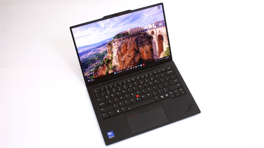 An open, black laptop against a white background with a picture of a building built into a cliffside showing on the screen. 