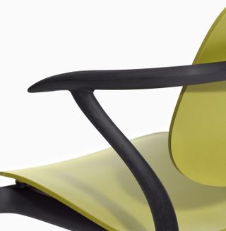 A view of part of a yellow, wooden chair with black, wooden arm