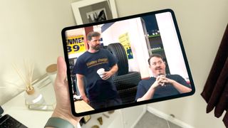 Apple iPad Pro 13-inch M4 tablet held in hand with two men on screen