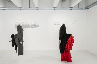 Installation image of Yohji Yamamoto exhibition at 10 Corso Como featuring sculptural black, white and red dresses