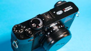 The Fujifilm X100VI mirrorless camera against a blue background.