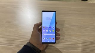 Sony Xperia 10 VI in hand with a wood table background