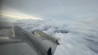 a large swirling storm can be seen off the wing of an aircraft