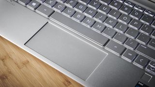 HP Spectre x360 (2021) on a wooden desk showing off its trackpad and part of its keyboard