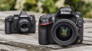 Two cameras sitting next to each other on a wooden table