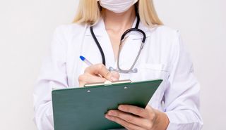 Female doctor writing on a clipboard.