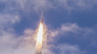 a large white rocket flies through the sky above a cone of flame