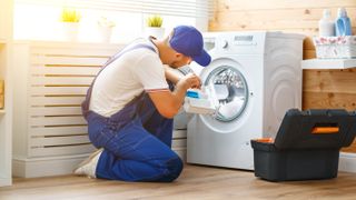 A washing machine being repaired by a handyman