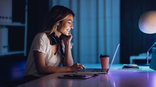 Young woman using a laptop inside at night