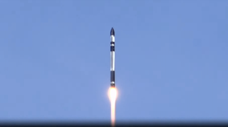 a black and white rocket rises into a blue sky