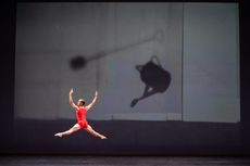 Man doing a solo on stage with a red unitard on