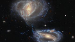 Two barred spiral galaxies, known as NGC 7733 and NGC 7734, are in the process of merging. The lower galaxy has a dusty knot atop its upper arm, which marks a third galactic companion.