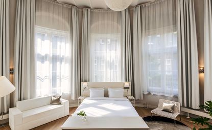 Bedroom in neutral tones, situated inside a huge, double-height bay window