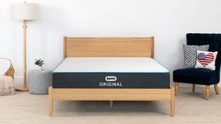 Bear Original Mattress placed on a wooden bedframe next to a black highback chair