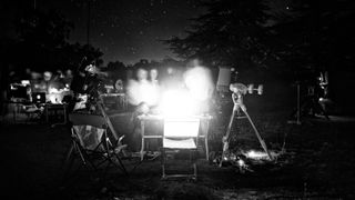 a black and white photograph of a group of people crowded around a telescope