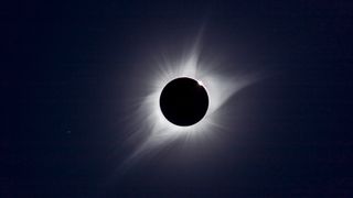 A composite of the August 21, 2017 total solar eclipse showing third contact – the end of totality – with sunlight beginning to reappear and the array of pink prominences along the limb of the Sun Seconds later the emerging Sun and diamond ring overwhelmed the large prominence Regulus is at lower left.