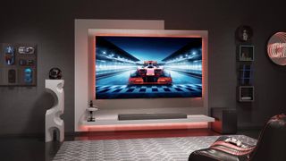 A TCL C74 Series TV wall-mounted in a modern lounge above a soundbar and next to a white sculpture. On screen is a racing game.