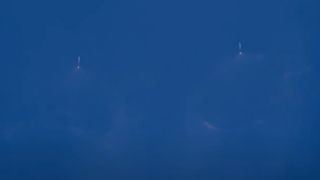 a large white rocket launches through a clear blue sky