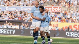 Erling Haaland (L) and Oscar Bobb (R) celebrate a goal in Manchester City&#039;s sky blue shirt and white shorts.