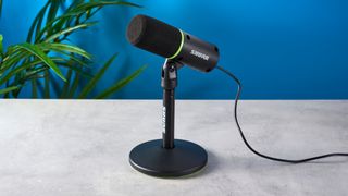 a photograph of a black and green small microphone with a muff and a USB-C connection port and a desktop stand