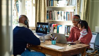 A man working from home while his wife and daughter work on a computer opposite